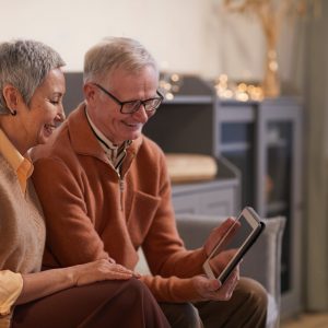 couple smiling while looking at a tablet computer
